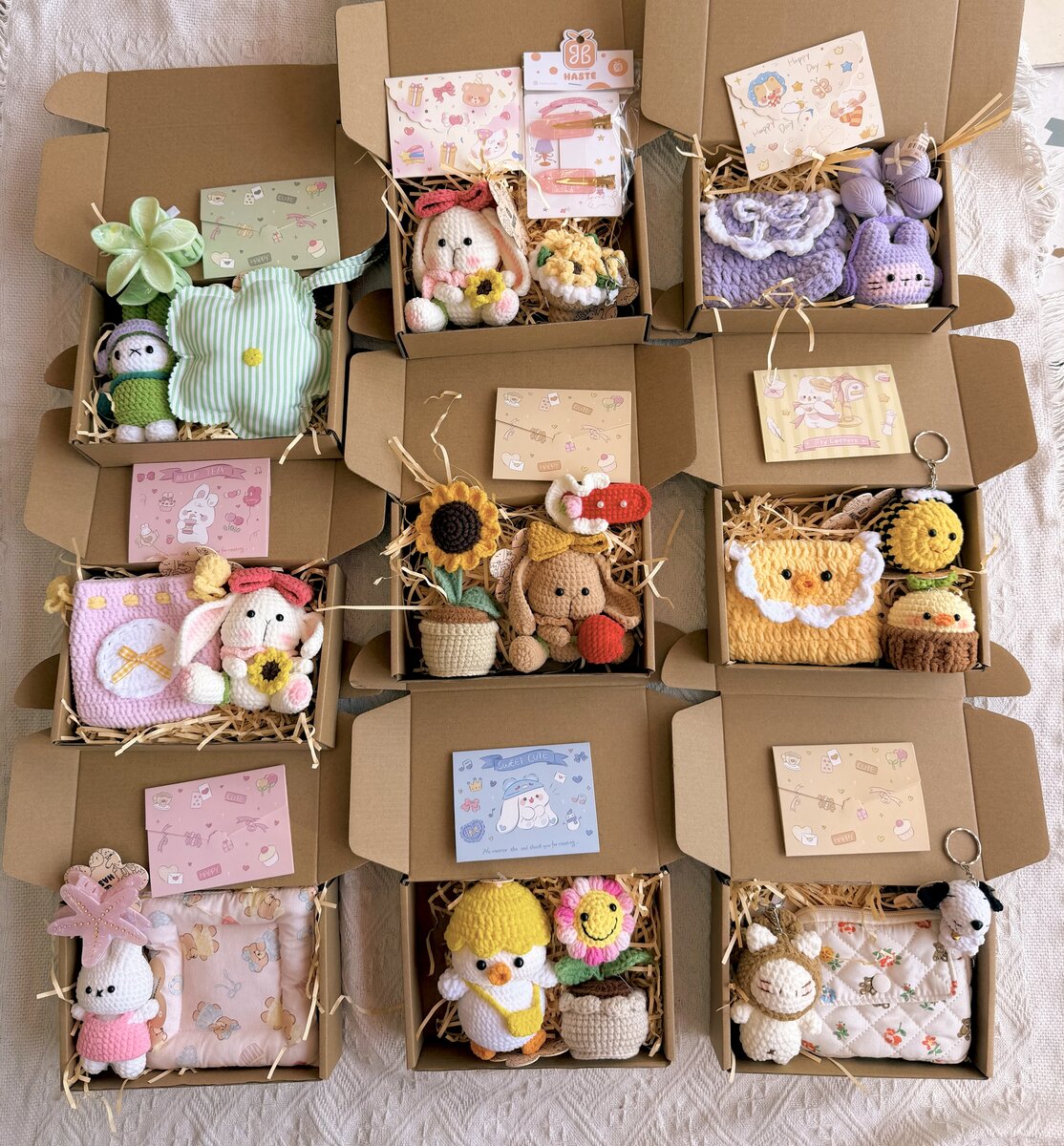 Chín hộp set quà handmade xếp cạnh nhau, mỗi hộp có thú len, ví hoặc chậu hoa mini