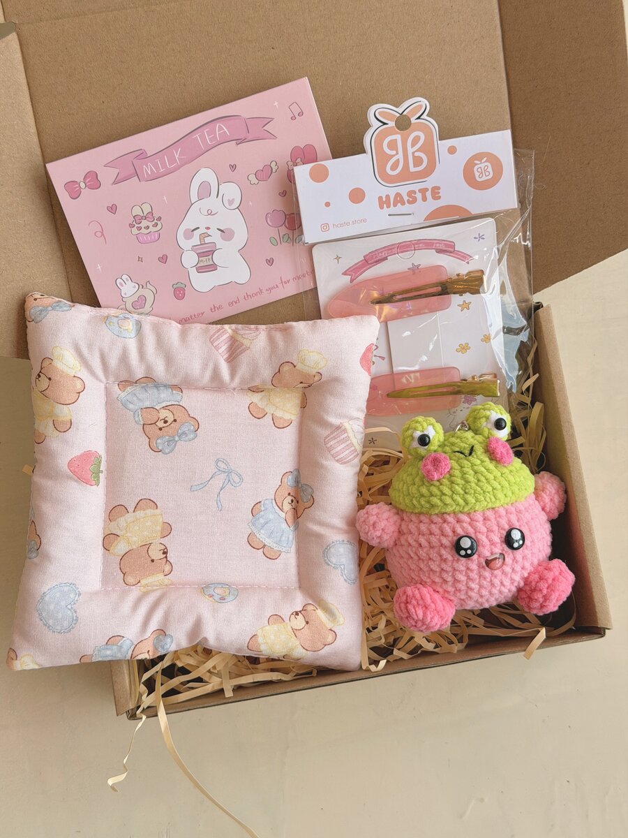 Hộp quà handmade có ếch len hồng đội mũ xanh, gối họa tiết gấu và kẹp tóc, kèm thiệp nhỏ